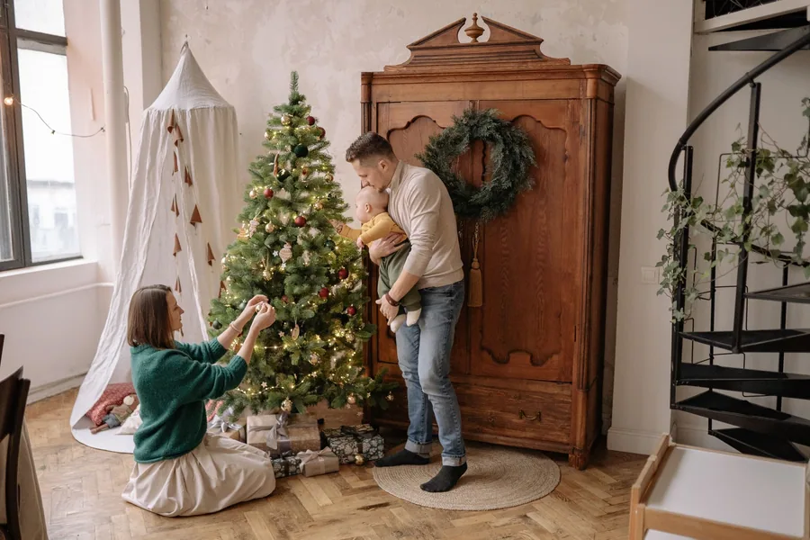 Familia decorando un árbol con adornos resistentes